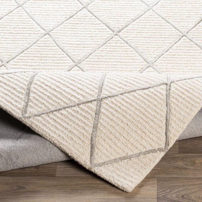 Ivory diamond lattice wool rug corner with tufted texture and outlined seam edges
