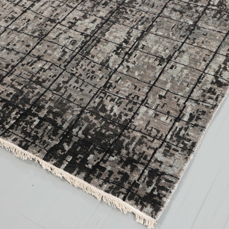 Grey and charcoal grid abstract rug with fringed border at corner
