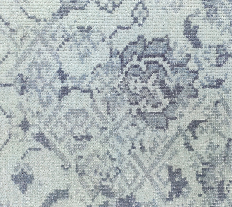 Dusty blue oriental rug close-up with distressed medallion motifs, flat weave texture.