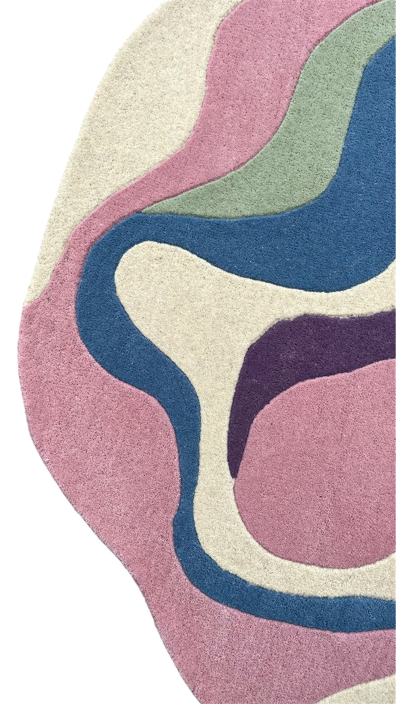 Serpentine irregular area rug featuring pink, blue, green, plum and ivory abstract shapes