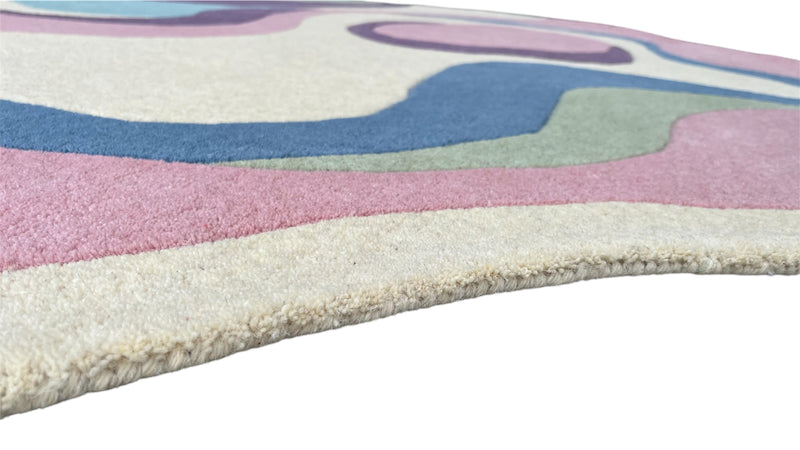 Close-up side view of Serpentine hand-tufted wool rug with soft pastel colors and textured pile